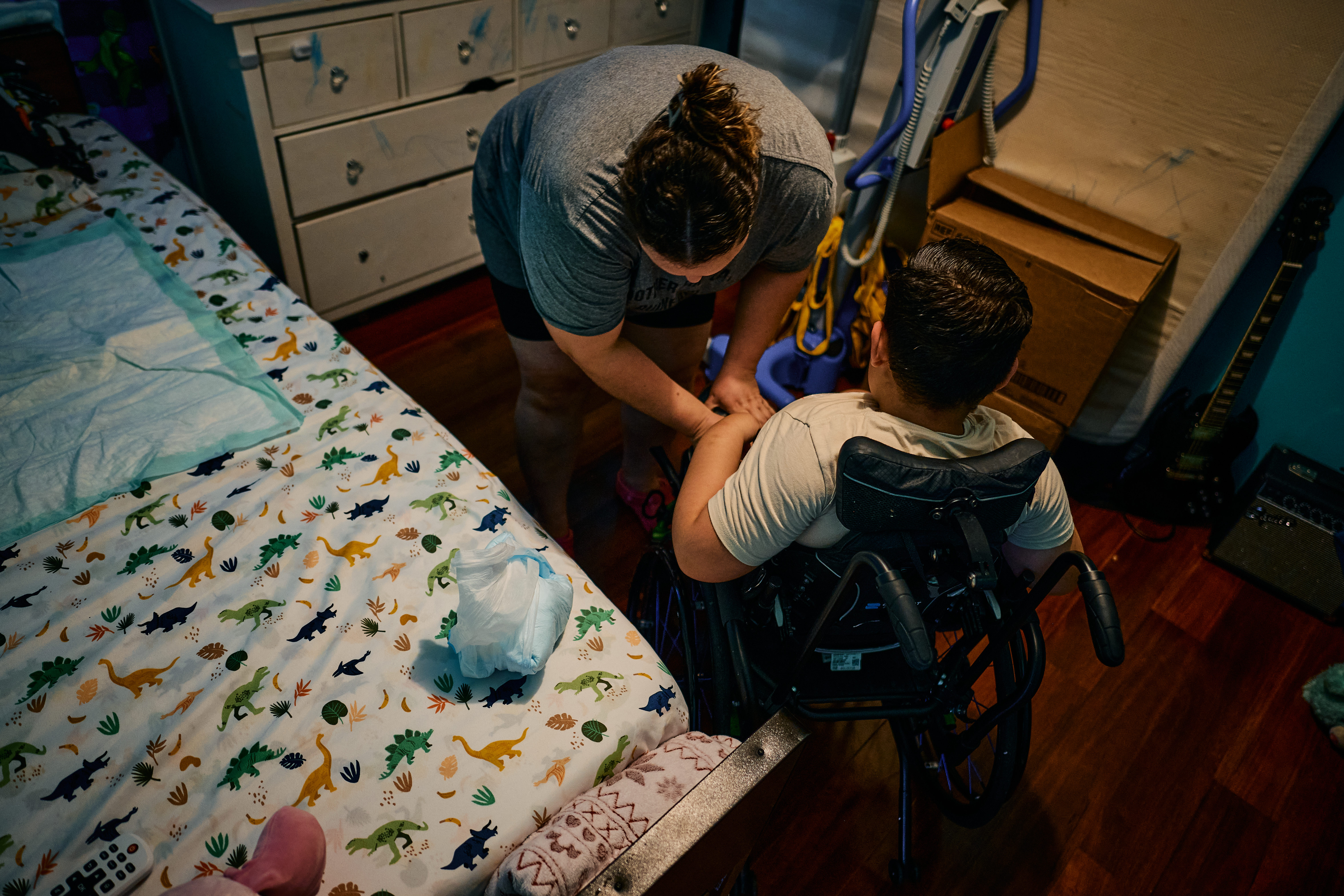 Gabriella returns her son, Daneri, to his wheelchair after she catheters him and changes his diaper on June 18. Daneri, who has spina bifida, is paralyzed from the waist down. (William DeShazer/FTWP)