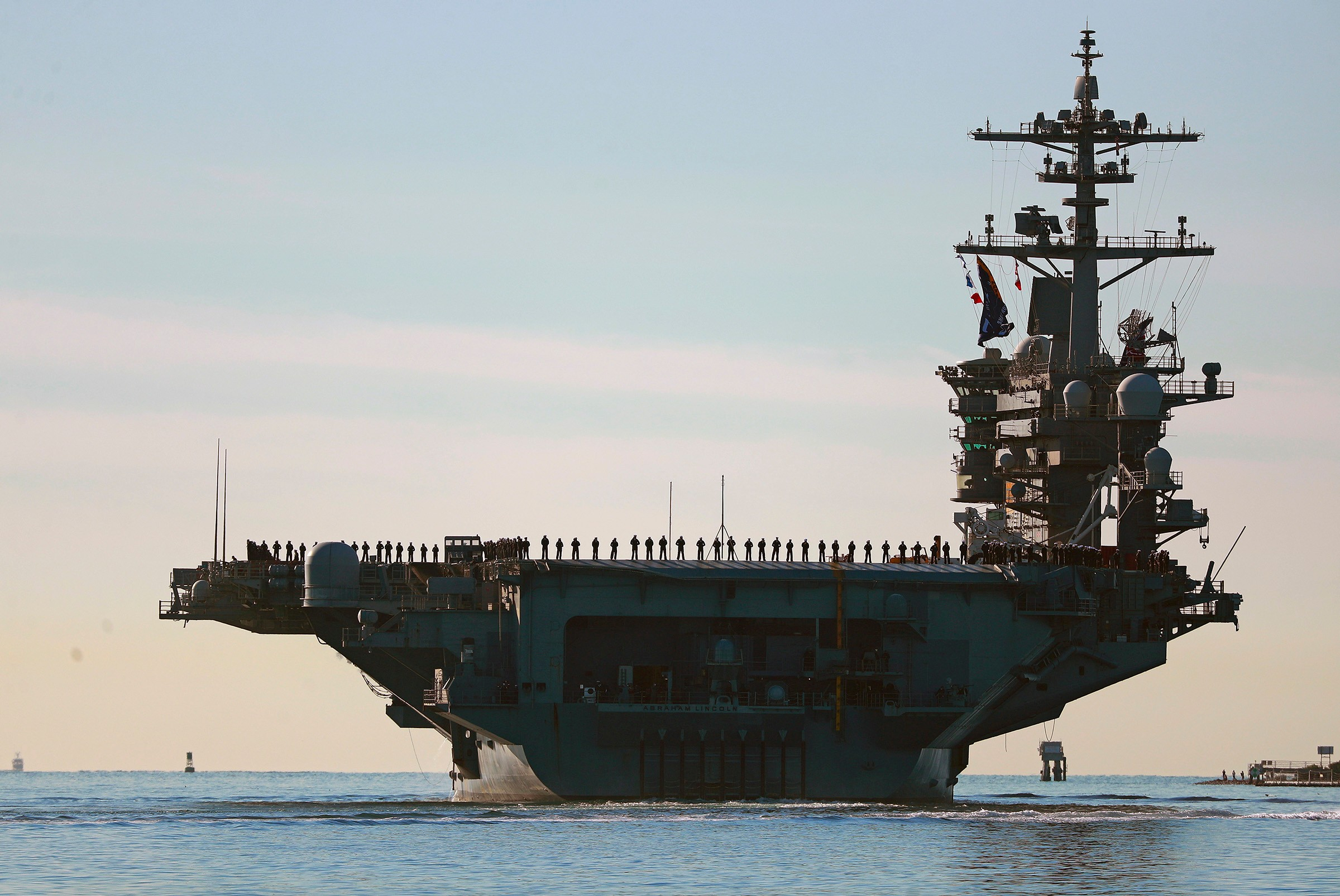 Sailors and Marines line the deck of the aircraft carrier USS Abraham Lincoln as it deploys from San Diego in 2021. (K.C. Alfred/San Diego Union-Tribune/AP)
