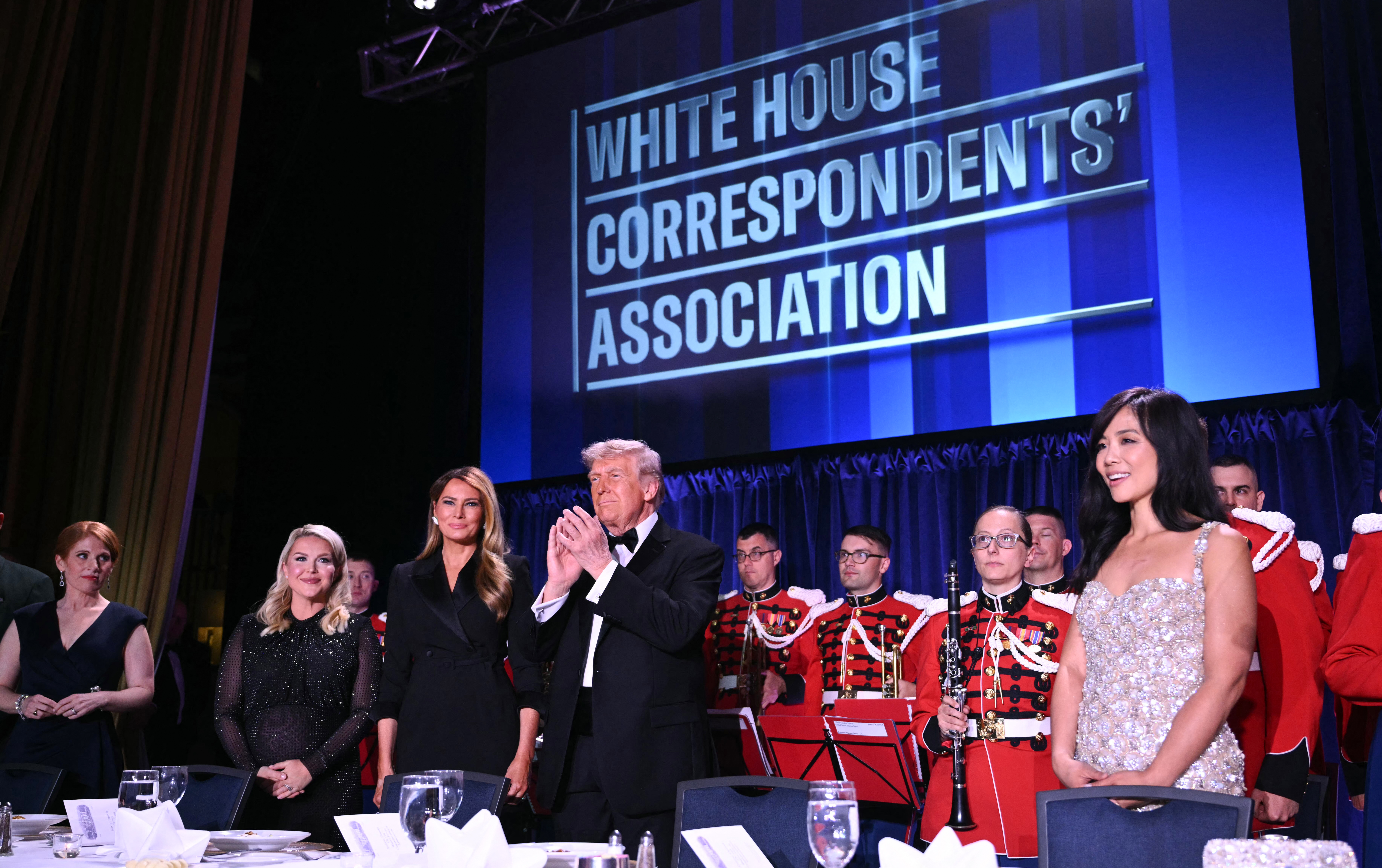 President Donald Trump claps alongside first lady Melania Trump prior to the shooting incident at the White House Correspondents' Association dinner on Saturday evening. Also pictured are journalist Karen Travers, far left, and press secretary Karoline Leavitt. (Mandel Ngan/AFP/Getty Images)