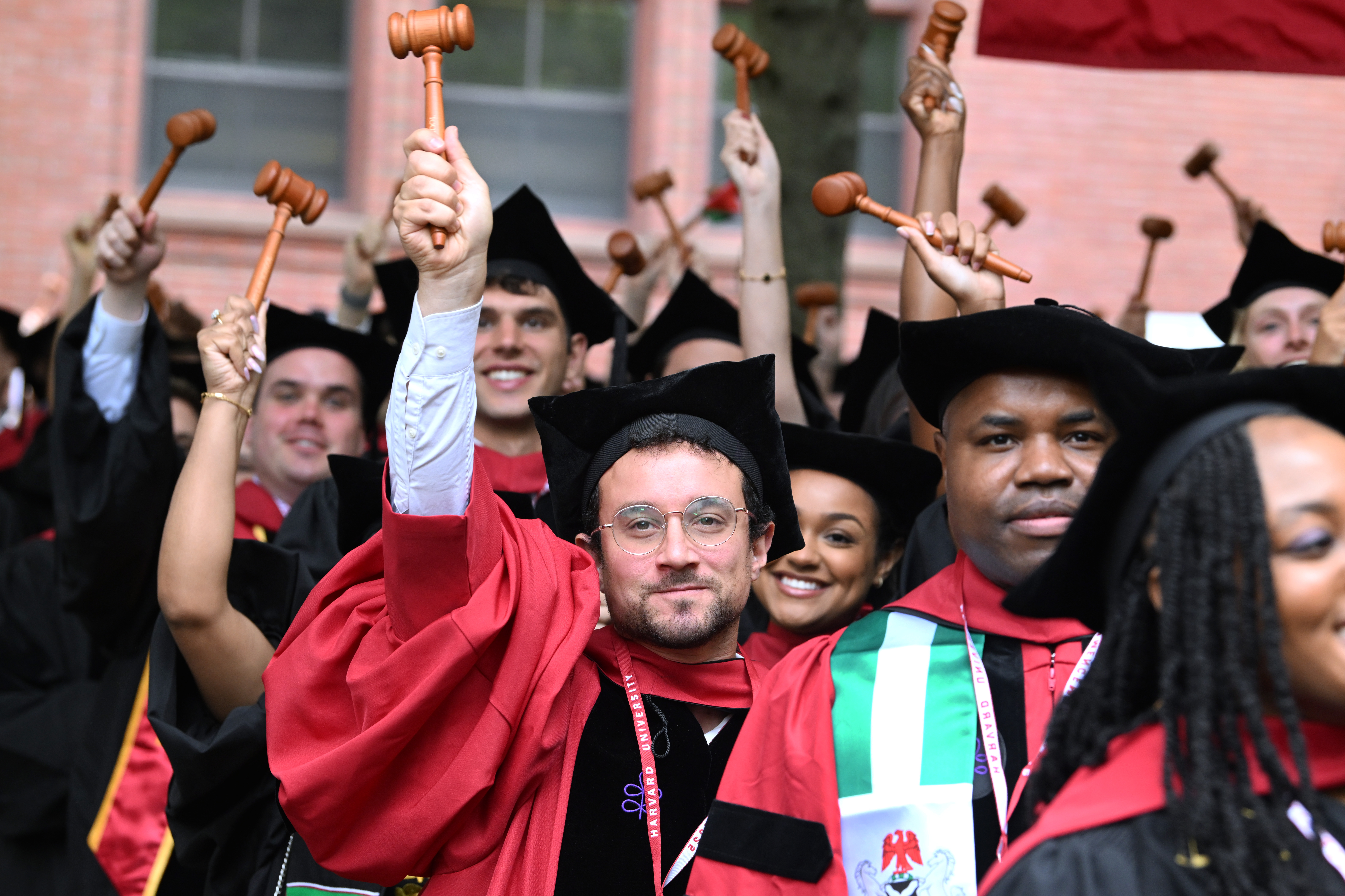 Graduates of Harvard Law School wave novelty gavels as they are conferred their degrees on May 29. (Josh Reynolds/For The Washington Post)