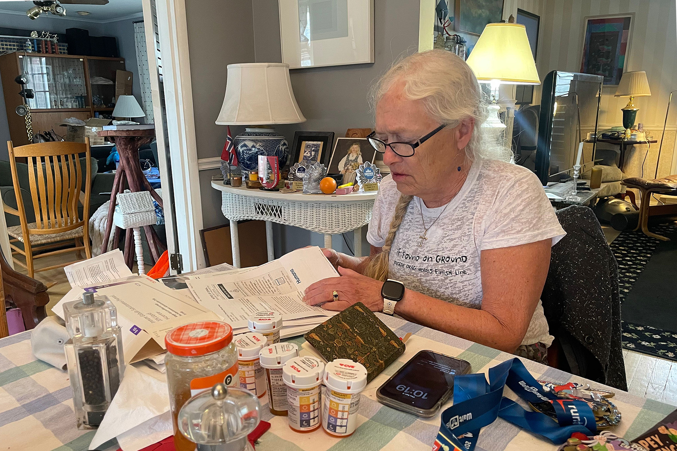 Hvatum sits at her dining room table in her suburban St. Louis home sorting through letters from her insurer. (Samantha Liss/KFF Health News)