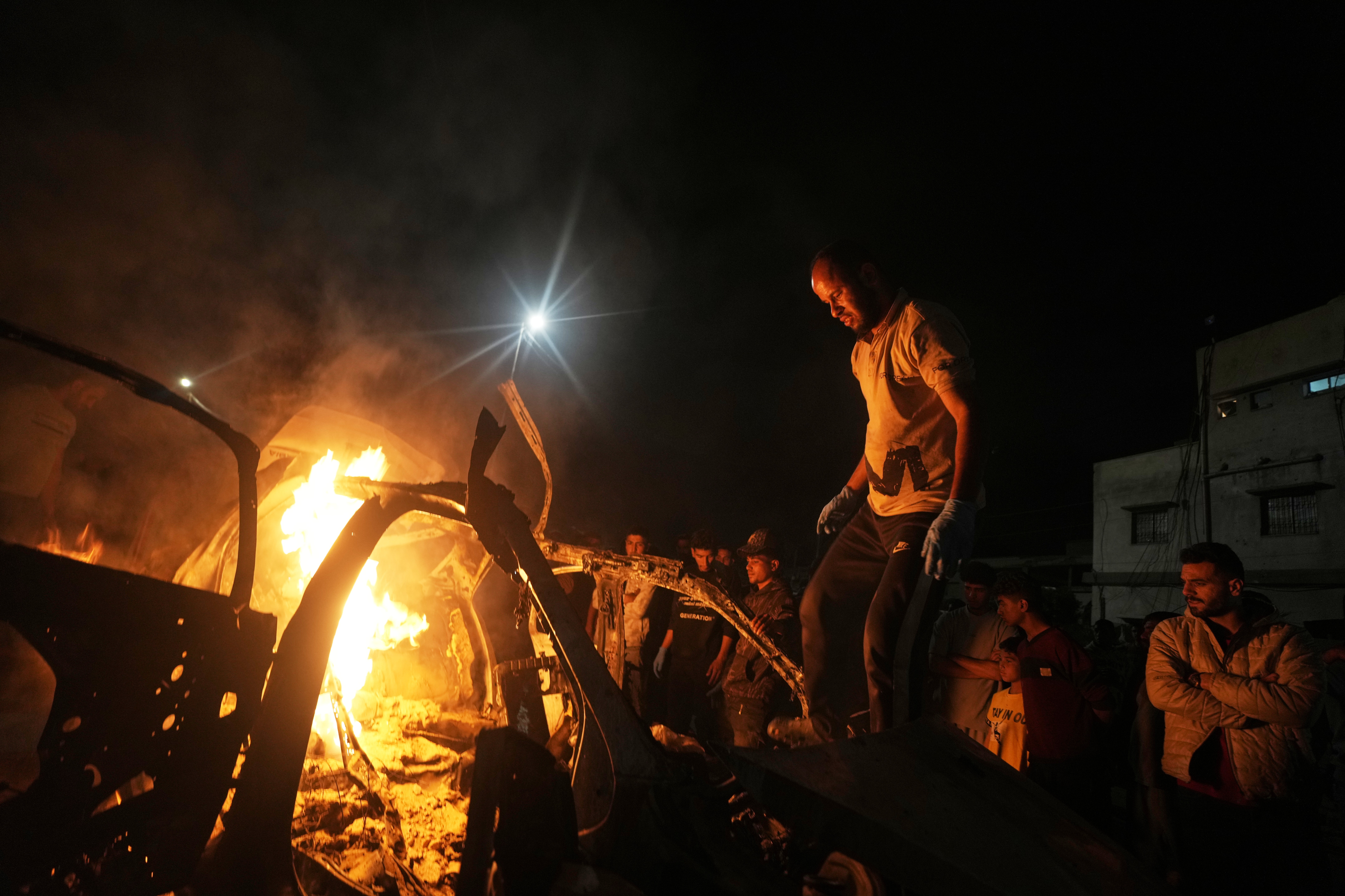 Palestinians gather around a vehicle struck by an Israeli strike in Gaza City on Friday. (Jehad Alshrafi/AP)