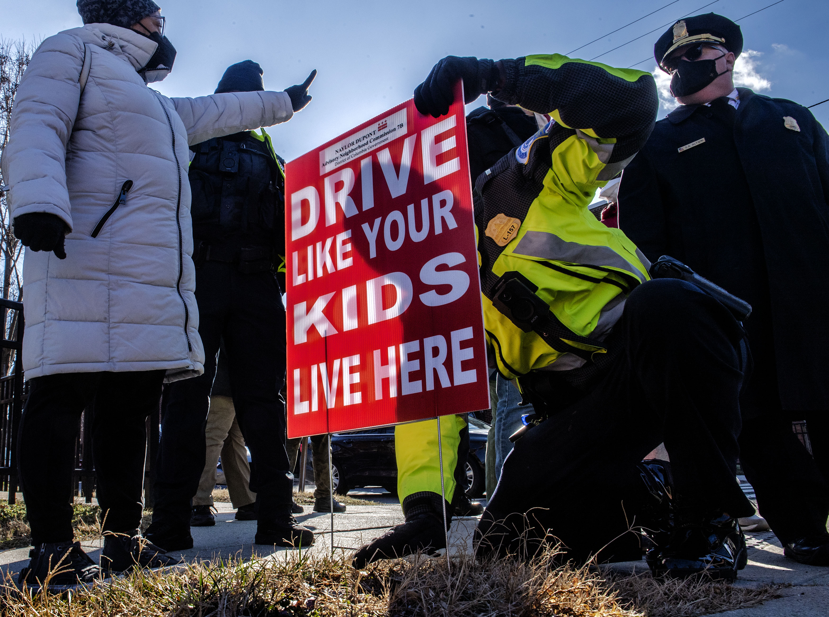 D.C. police Lt. Sean Hill installs a sign that says "Drive like your kids live here" near Q Street SE. (Bill O'Leary/The Washington Post)