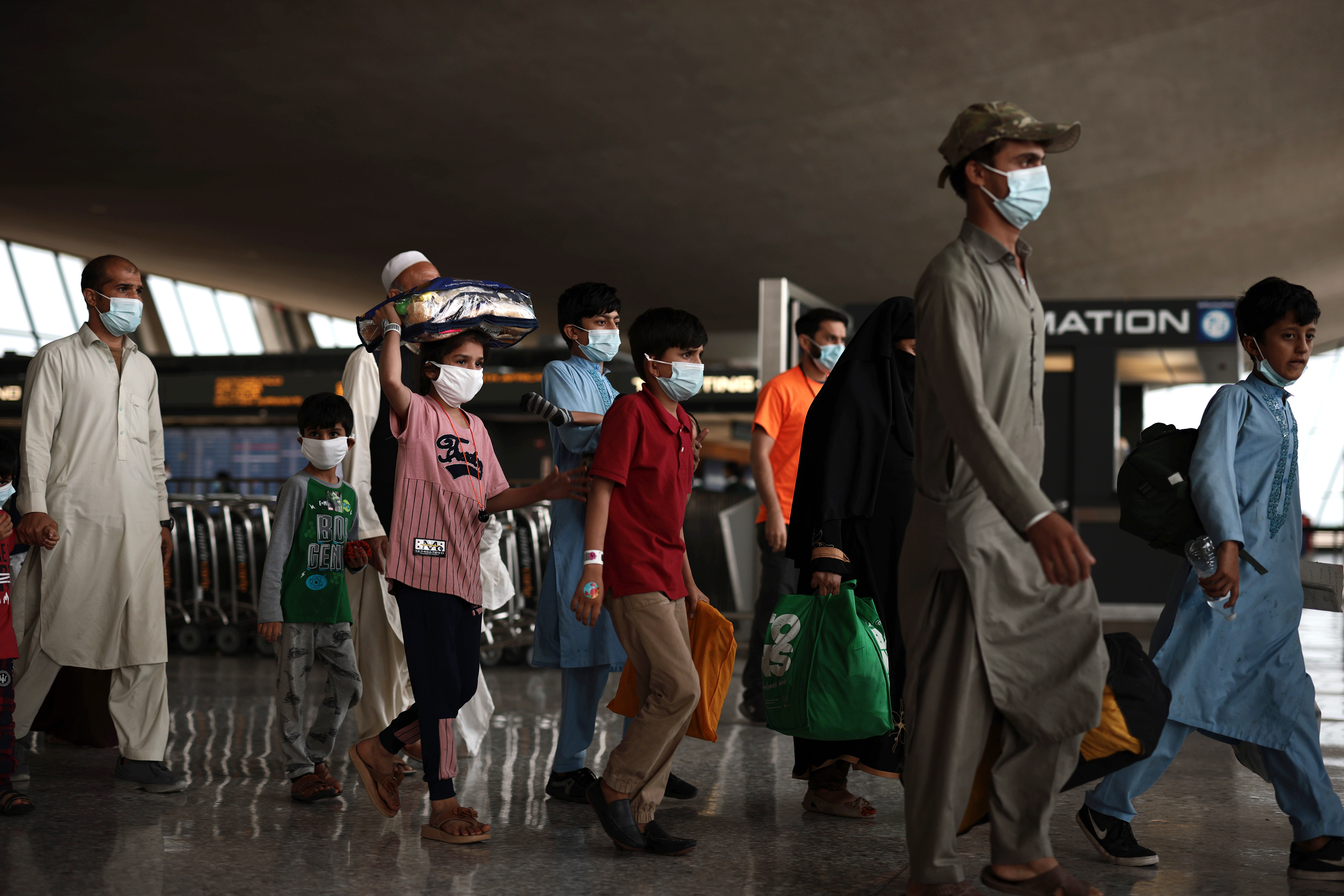Refugees walk through the departures terminal to a bus at Dulles International Airport after being evacuated from Kabul following the Taliban takeover of Afghanistan on Aug. 31, 2021. (Anna Moneymaker/Getty Images)
