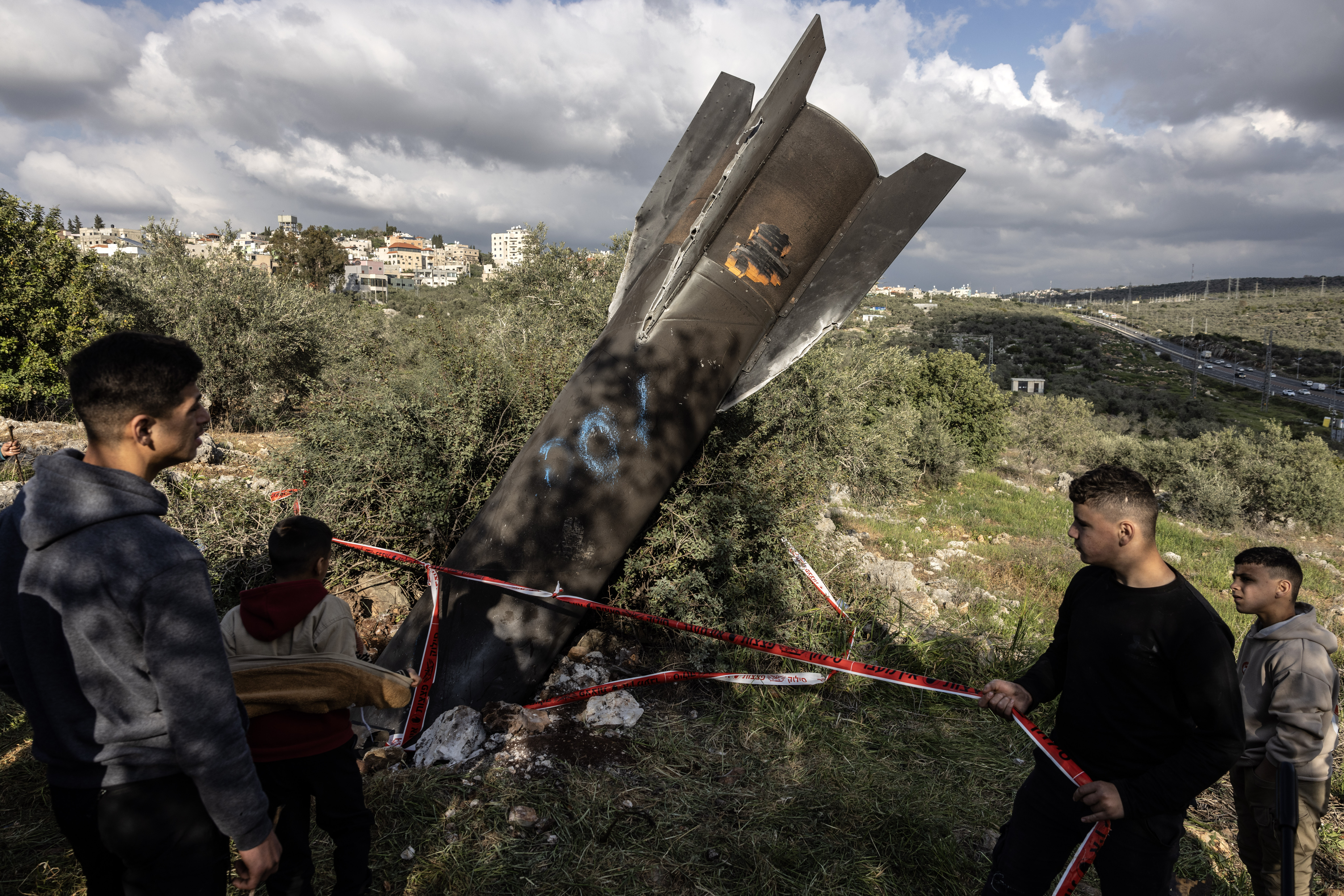 Palestinians visit the site where remnants of a missile fired from Iran are embedded in the ground in Kifl Haris, a village near Nablus in the Israeli-occupied West Bank, on Tuesday. (Heidi Levine/For The Washington Post)