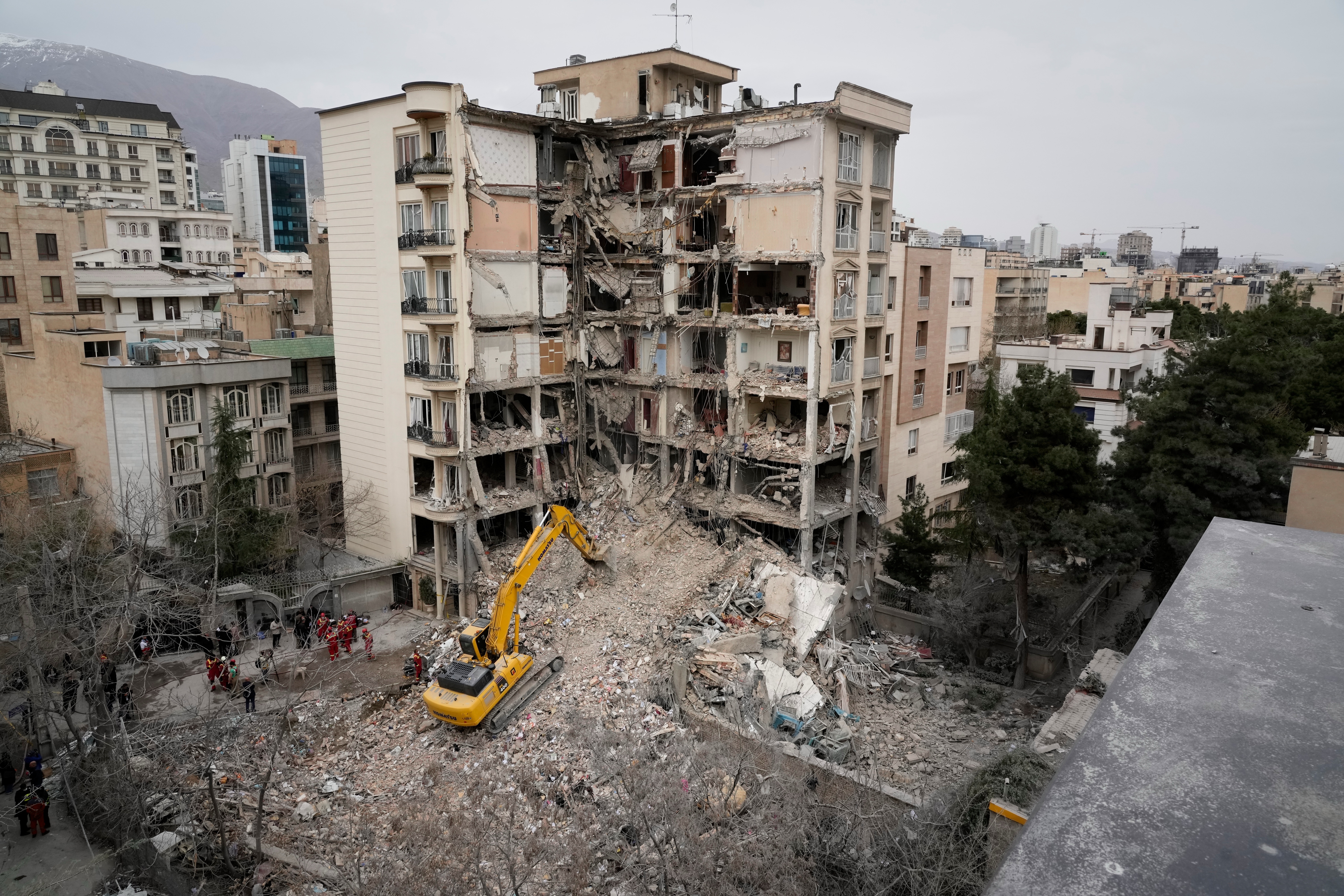 Iranian Red Crescent emergency workers use a bulldozer Monday to clear rubble from a residential building that was hit in an earlier U.S.-Israeli strike in Tehran. (Vahid Salemi/AP)
