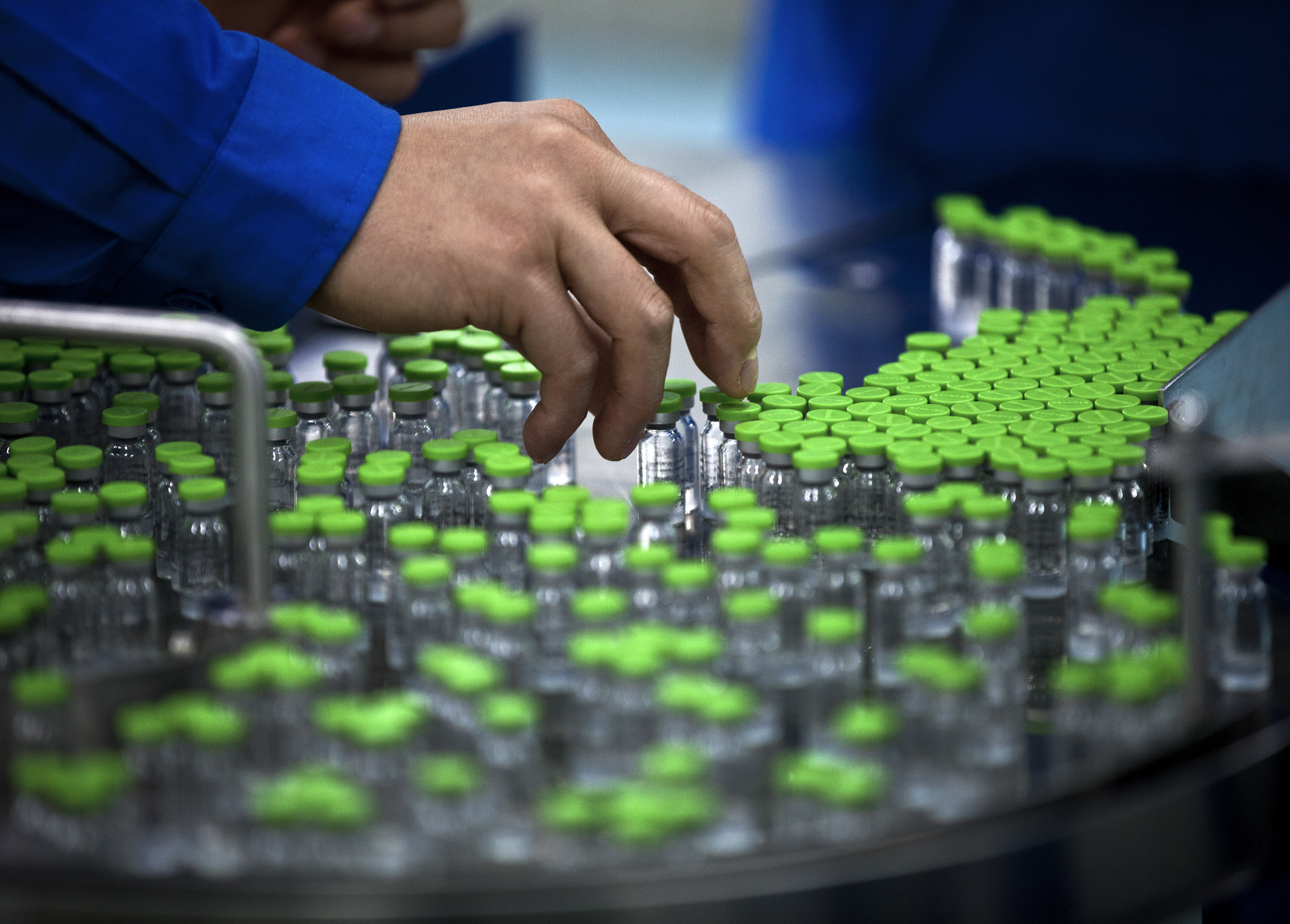 A worker inspects labels on vials containing H5N1 flu vaccine during production. (Andy Wong/AP)