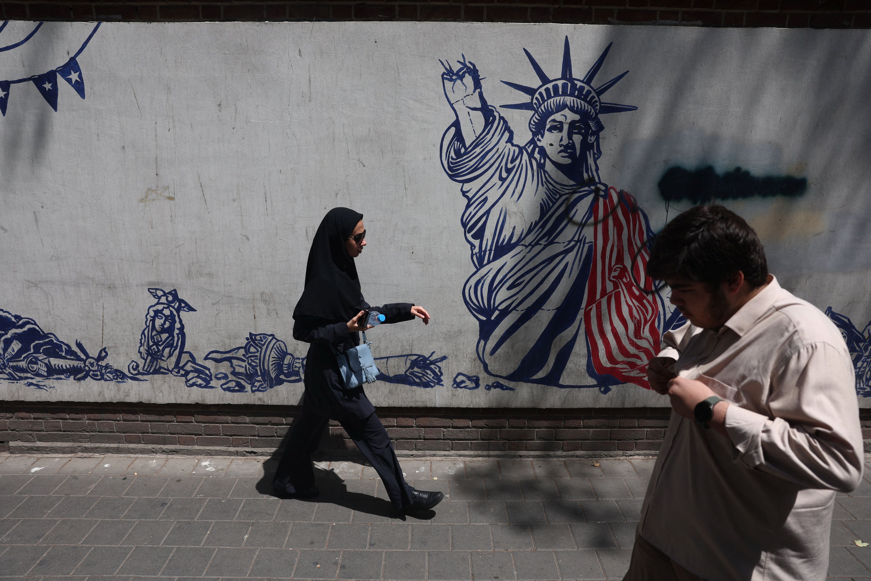People walk near an anti-U.S. mural in Tehran on Wednesday. (Majid Asgaripour/Reuters)