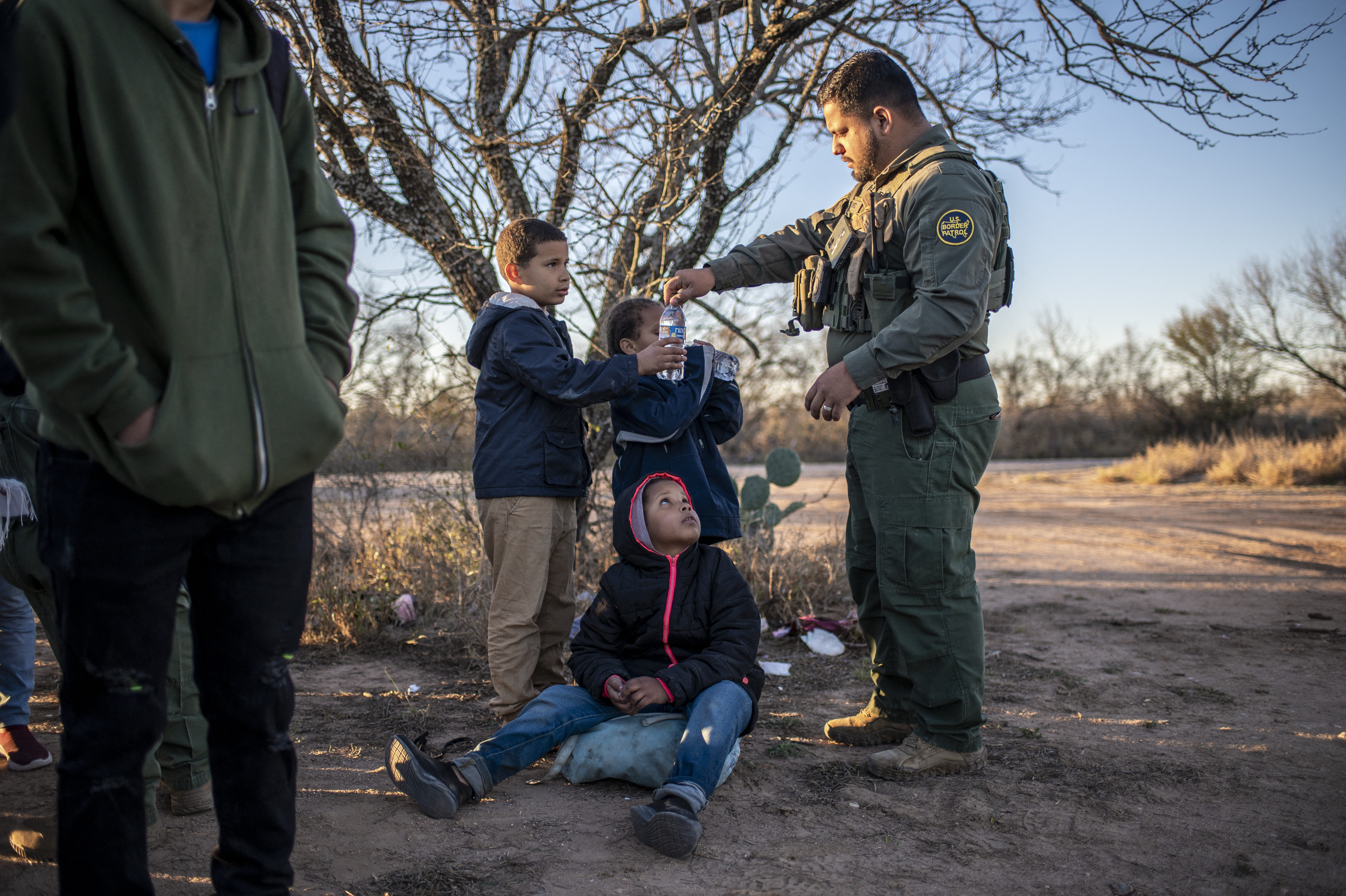 A Border Patrol agent offers water to a group of children apprehended by immigration authorities near a highway outside of Eagle Pass, Texas, on Feb. 4, 2024. (Sergio Flores/AFP/Getty Images)